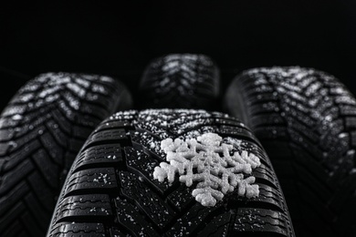 Photo of Set of new winter tires on black background, closeup