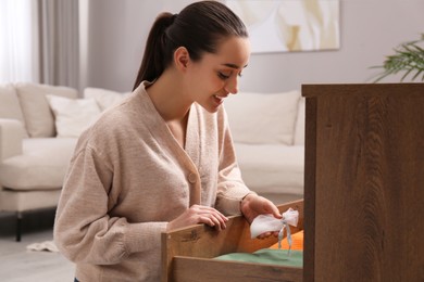 Woman putting scented sachet into drawer with clothes Photo of Woman putting scented sachet into drawer with clothes