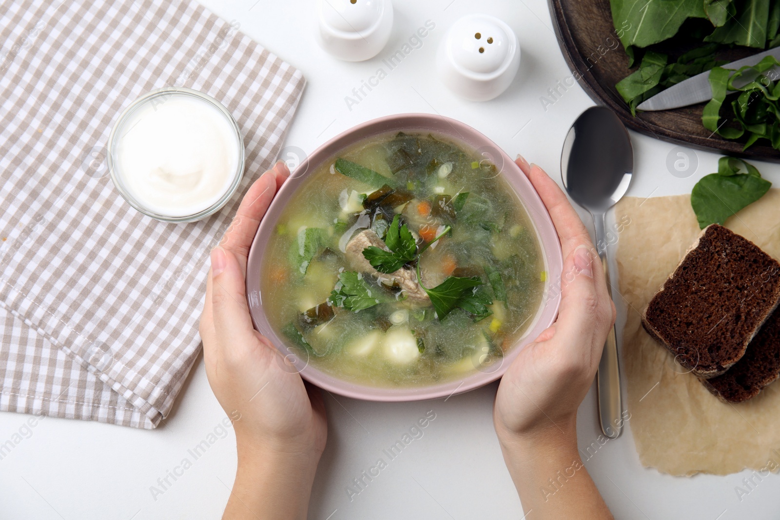 Woman eating delicious sorrel soup with meat and parsley at white table, top view Photo of Woman eating delicious sorrel soup with meat and parsley at white table, top view