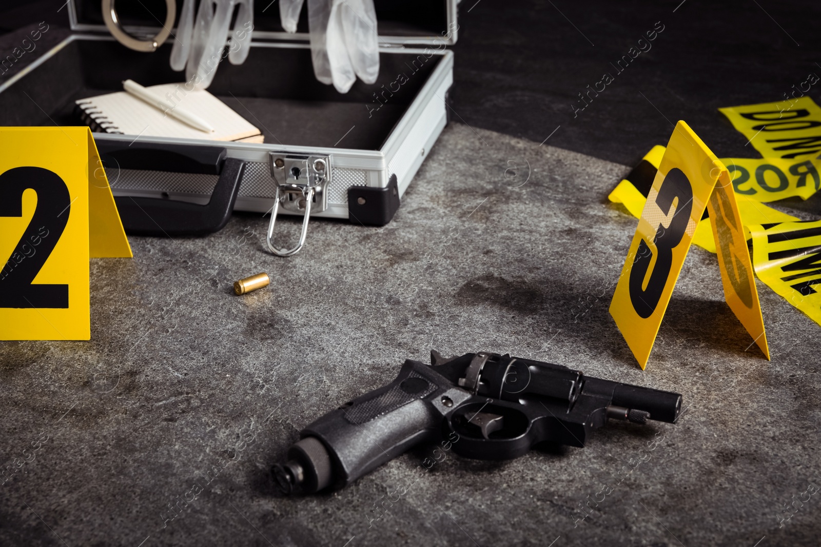 Shell casing, gun and crime scene marker on grey stone table Photo of Shell casing, gun and crime scene marker on grey stone table