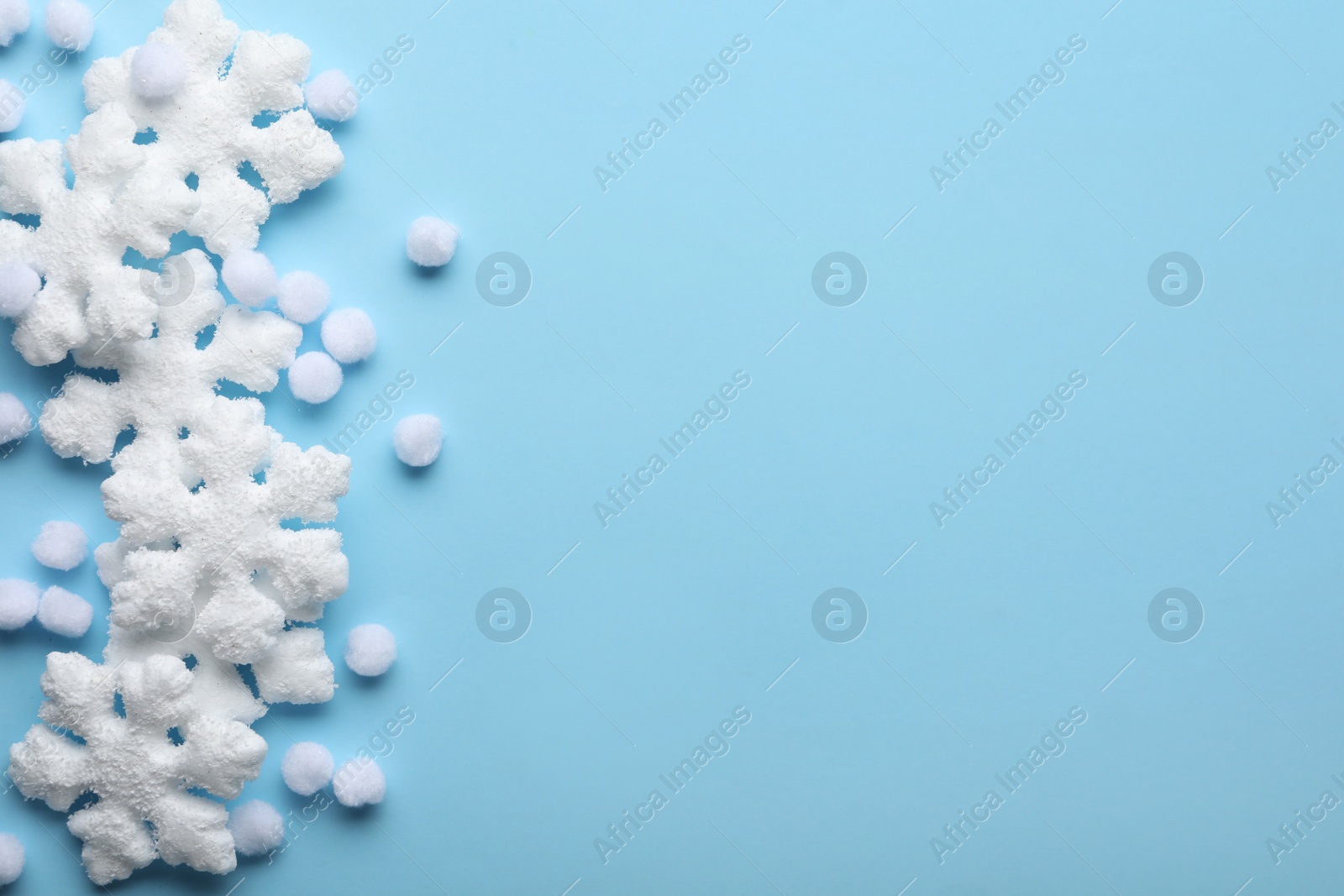 Beautiful snowflakes and decorative balls on light blue background, flat lay. Space for text Photo of Beautiful snowflakes and decorative balls on light blue background, flat lay. Space for text