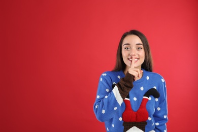 Photo of Young woman in Christmas sweater on red background, space for text