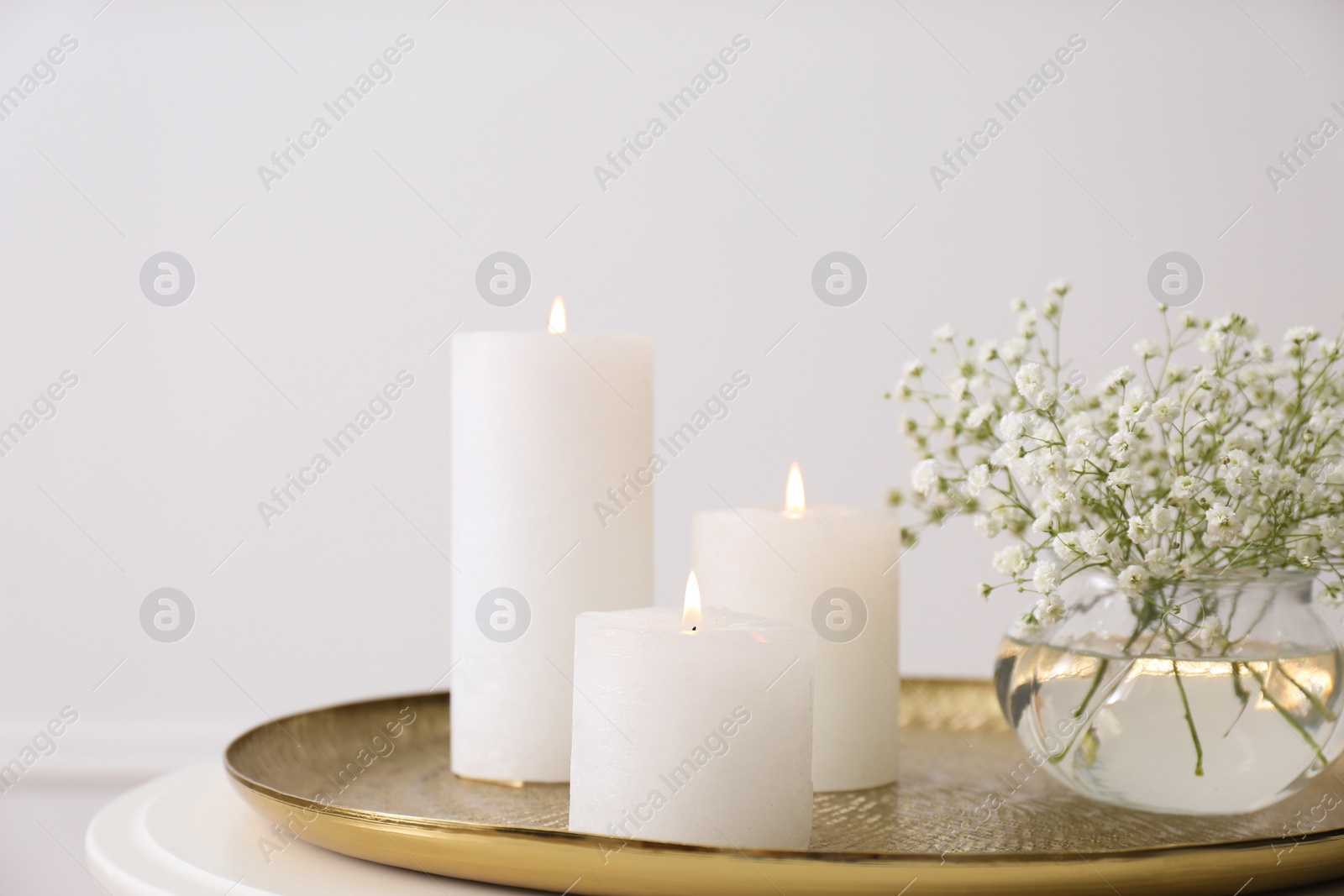 Vase with beautiful flowers and burning candles on table indoors, closeup. Interior elements Photo of Vase with beautiful flowers and burning candles on table indoors, closeup. Interior elements