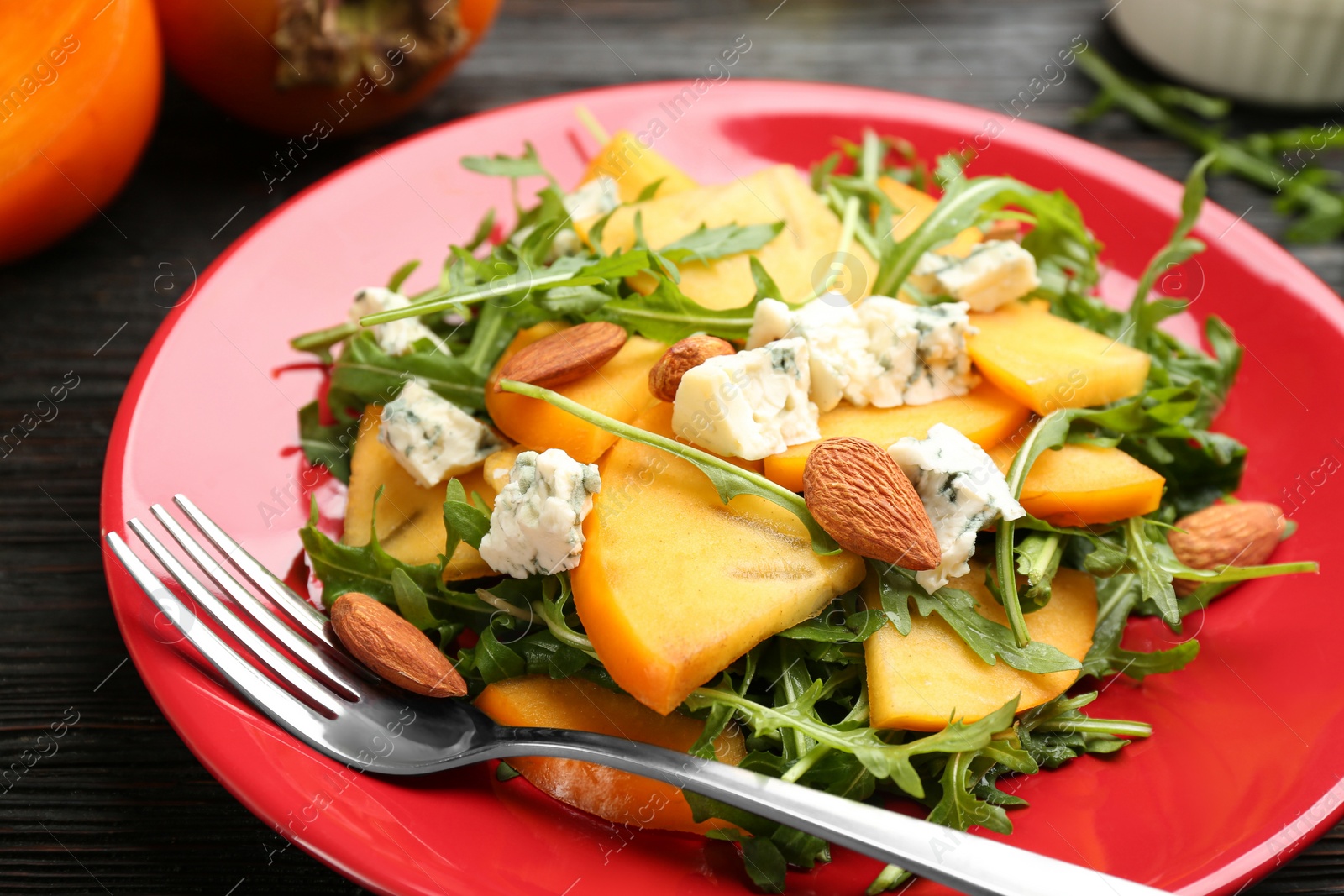 Delicious persimmon salad with blue cheese and arugula on table, closeup Photo of Delicious persimmon salad with blue cheese and arugula on table, closeup