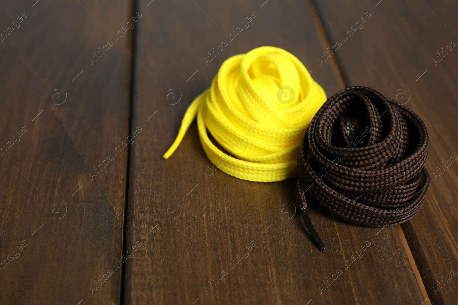 Yellow and brown shoelaces on wooden background. Space for text Photo of Yellow and brown shoelaces on wooden background. Space for text