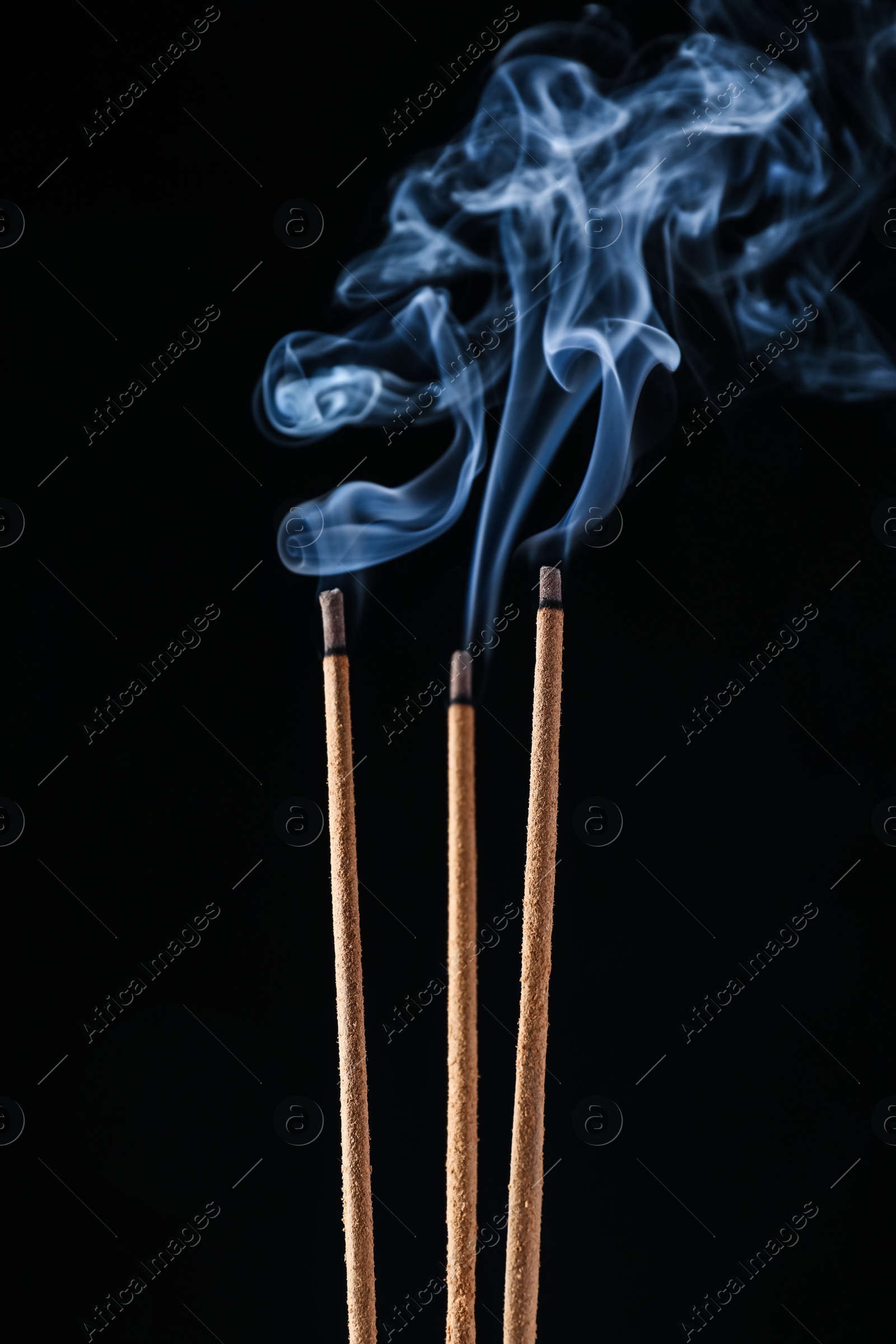 Incense sticks smoldering on black background, closeup Photo of Incense sticks smoldering on black background, closeup