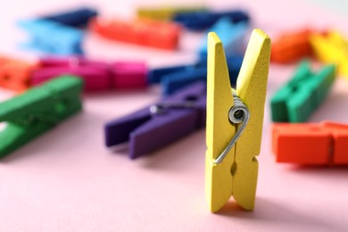 Yellow clothespin standing among lying ones on pink background. Diversity concept Photo of Yellow clothespin standing among lying ones on pink background. Diversity concept