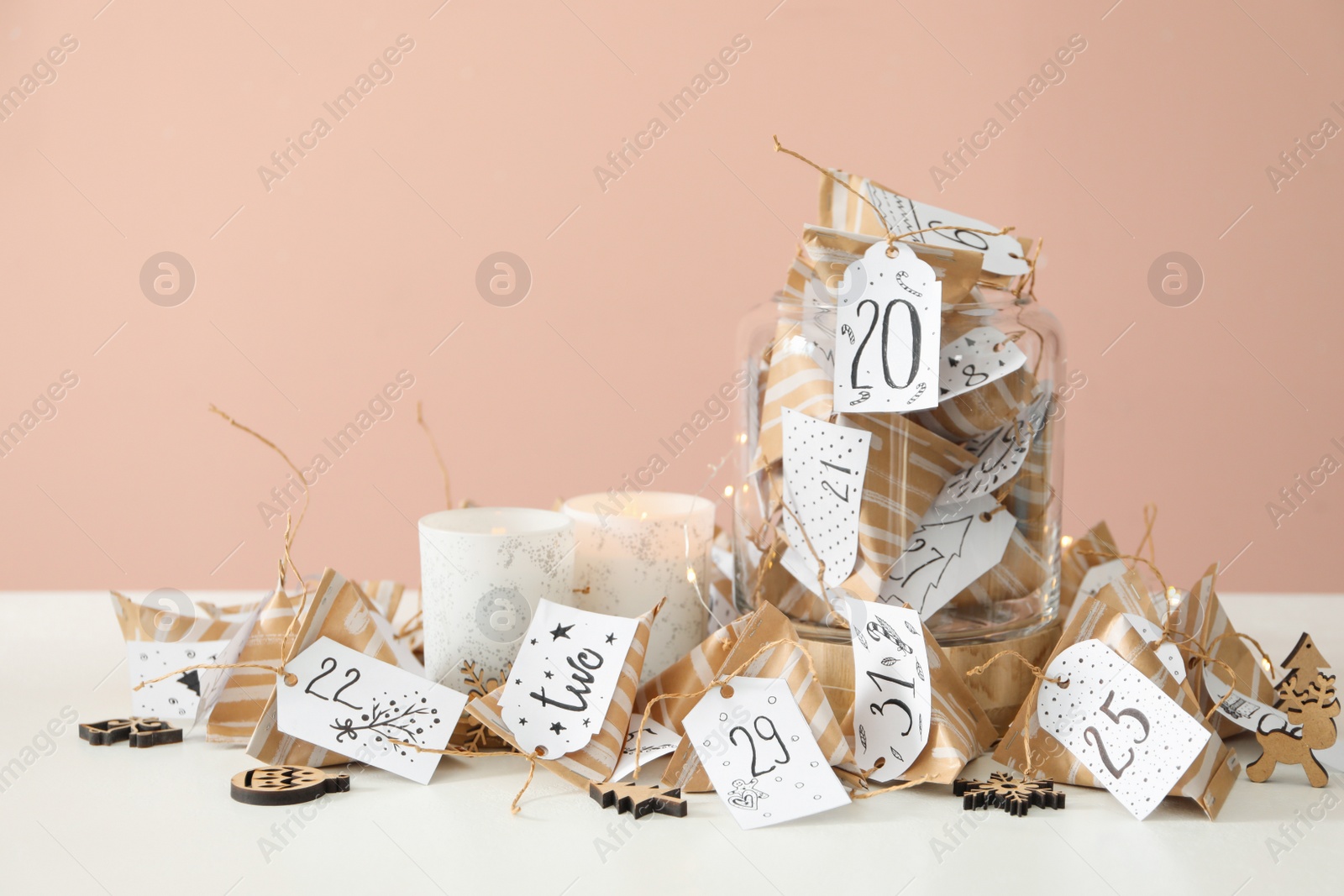 Christmas advent calendar with small gifts and burning candles on white table Photo of Christmas advent calendar with small gifts and burning candles on white table