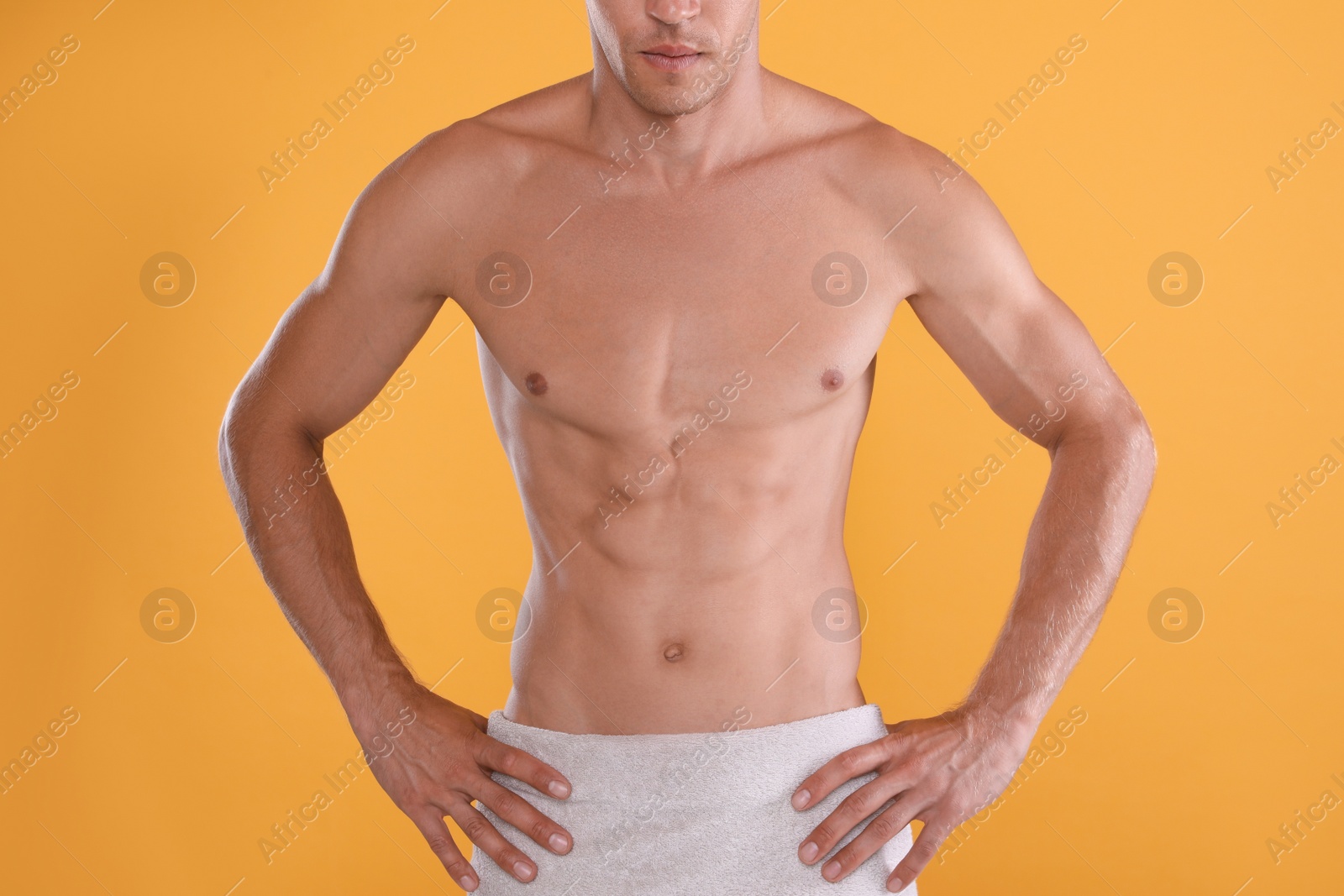 Shirtless man with slim body and towel wrapped around his hips on yellow background, closeup Photo of Shirtless man with slim body and towel wrapped around his hips on yellow background, closeup