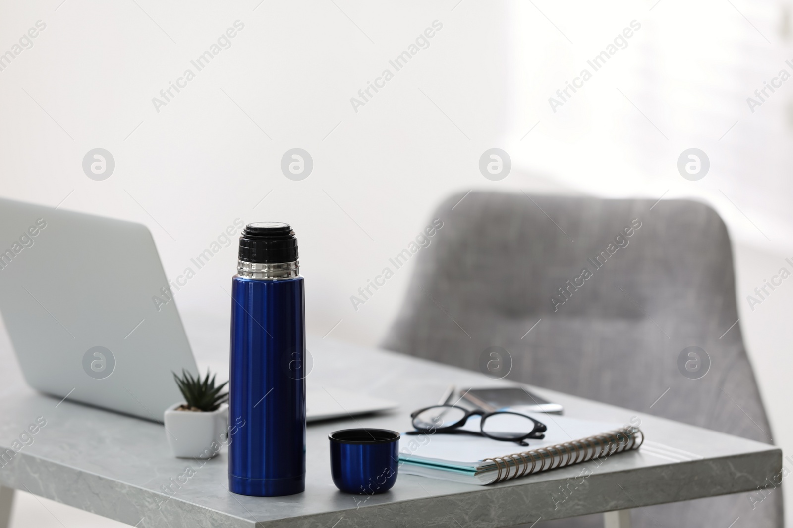 Thermo bottle on table in modern office Photo of Thermo bottle on table in modern office