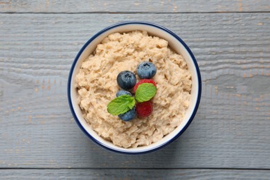 Tasty oatmeal porridge with berries on grey wooden table, top view Photo of Tasty oatmeal porridge with berries on grey wooden table, top view