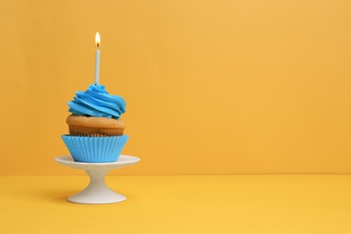 Birthday cupcake with candle on color background Photo of Birthday cupcake with candle on color background