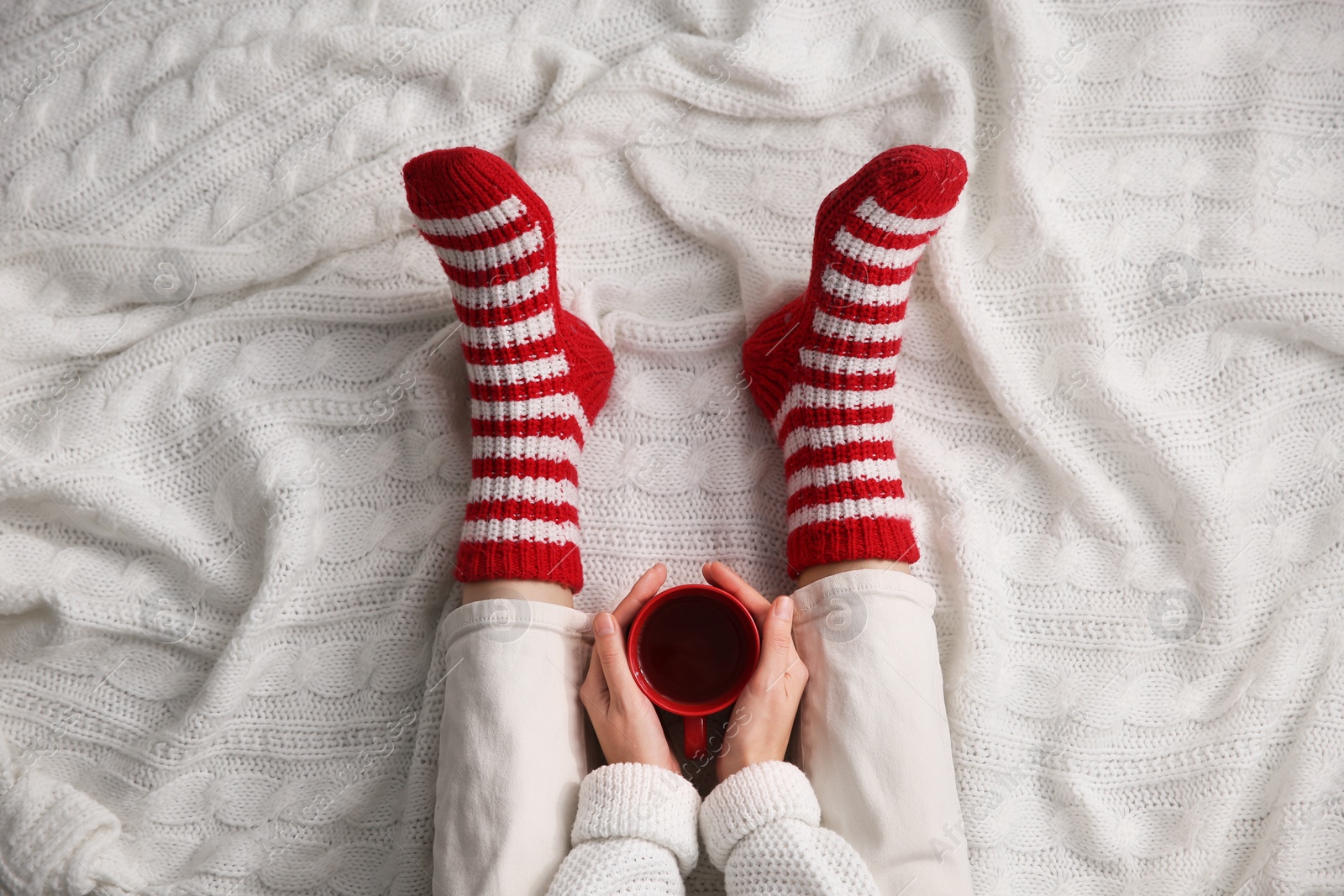 Woman relaxing with cup of hot winter drink on knitted plaid, top view. Cozy season Photo of Woman relaxing with cup of hot winter drink on knitted plaid, top view. Cozy season