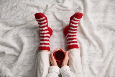 Woman relaxing with cup of hot winter drink on knitted plaid, top view. Cozy season Photo of Woman relaxing with cup of hot winter drink on knitted plaid, top view. Cozy season