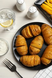 Delicious homemade Hasselback potatoes served on white wooden table, flat lay Photo of Delicious homemade Hasselback potatoes served on white wooden table, flat lay