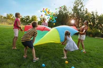 Group of children and teachers playing with rainbow playground parachute on green grass. Summer camp activity Photo of Group of children and teachers playing with rainbow playground parachute on green grass. Summer camp activity