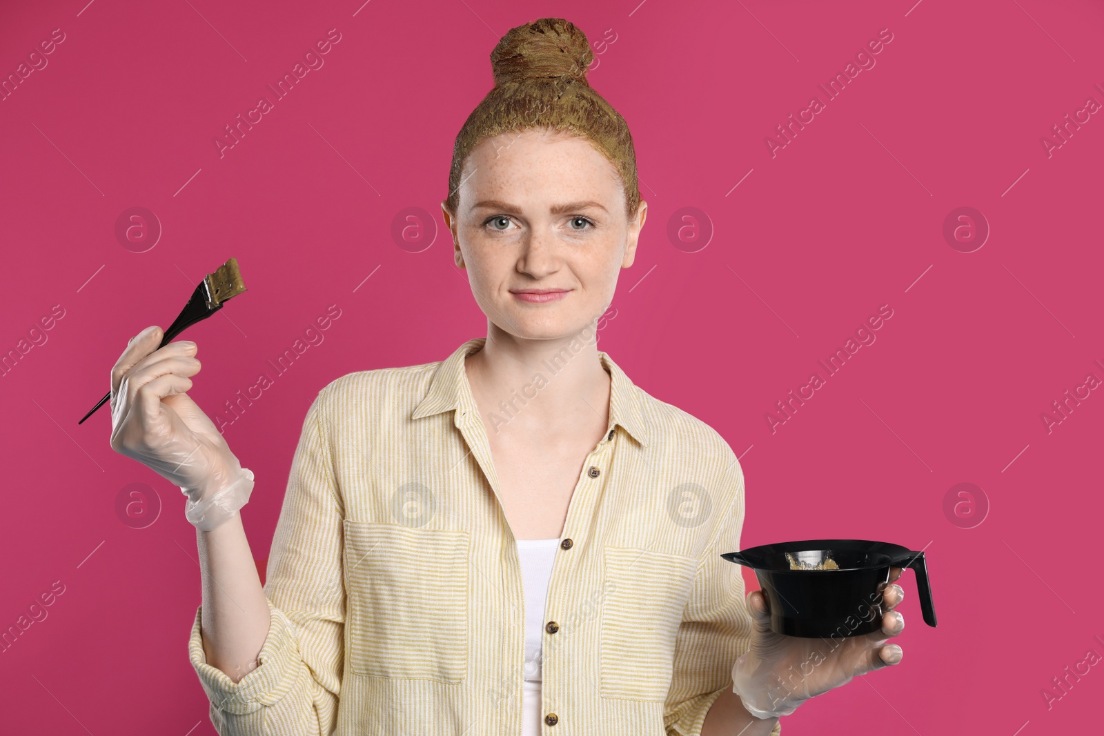 Young woman dyeing her hair with henna on pink background Photo of Young woman dyeing her hair with henna on pink background