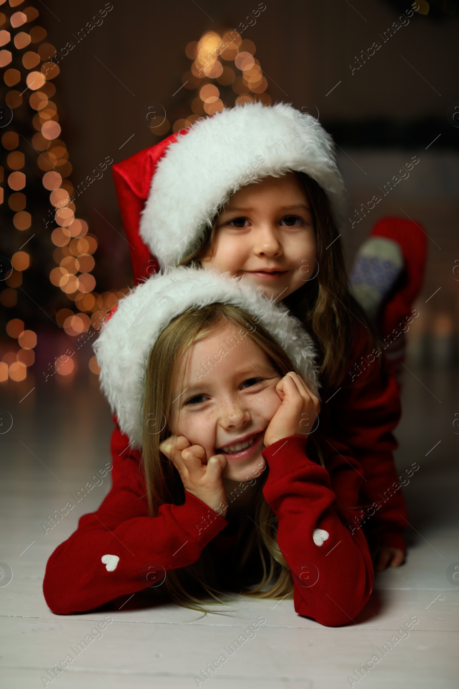 Cute little children wearing Santa hats at home. Christmas time Photo of Cute little children wearing Santa hats at home. Christmas time