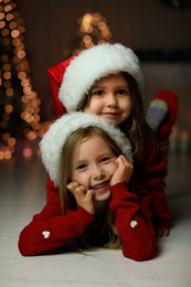 Cute little children wearing Santa hats at home. Christmas time Photo of Cute little children wearing Santa hats at home. Christmas time