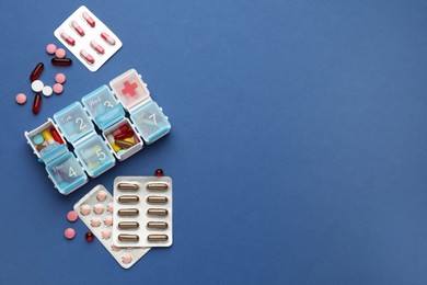 Plastic box with different pills on blue background, flat lay. Space for text Photo of Plastic box with different pills on blue background, flat lay. Space for text