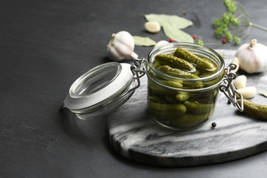 Glass jar of pickled cucumbers on black table. Space for text Photo of Glass jar of pickled cucumbers on black table. Space for text
