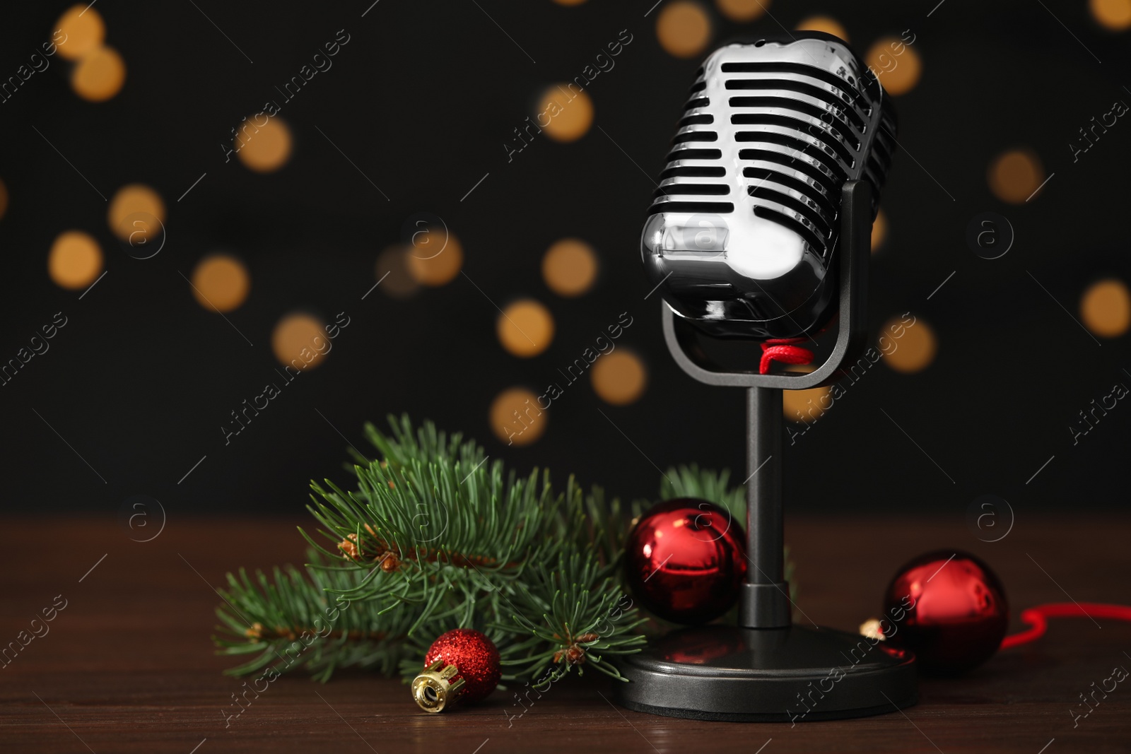 Retro microphone and festive decor on wooden table against blurred lights, space for text. Christmas music Photo of Retro microphone and festive decor on wooden table against blurred lights, space for text. Christmas music