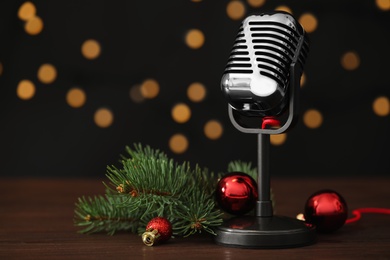 Retro microphone and festive decor on wooden table against blurred lights, space for text. Christmas music Photo of Retro microphone and festive decor on wooden table against blurred lights, space for text. Christmas music