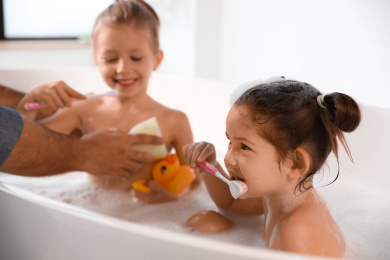 Photo of Young father with little daughters in bathroom