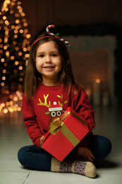 Photo of Cute little child with Christmas gift at home