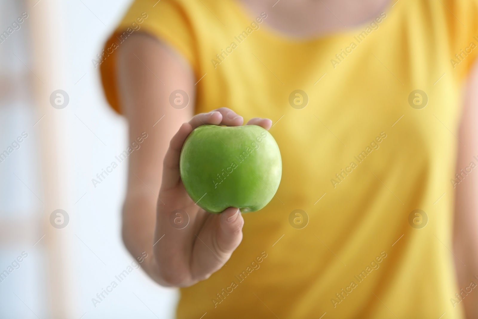 Woman holding ripe green apple on blurred background, closeup Photo of Woman holding ripe green apple on blurred background, closeup