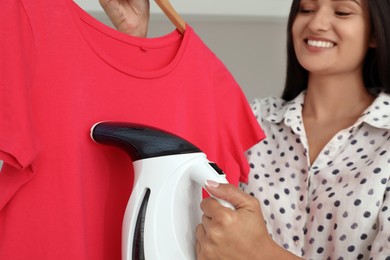 Woman steaming red t-shirt at home, closeup Photo of Woman steaming red t-shirt at home, closeup
