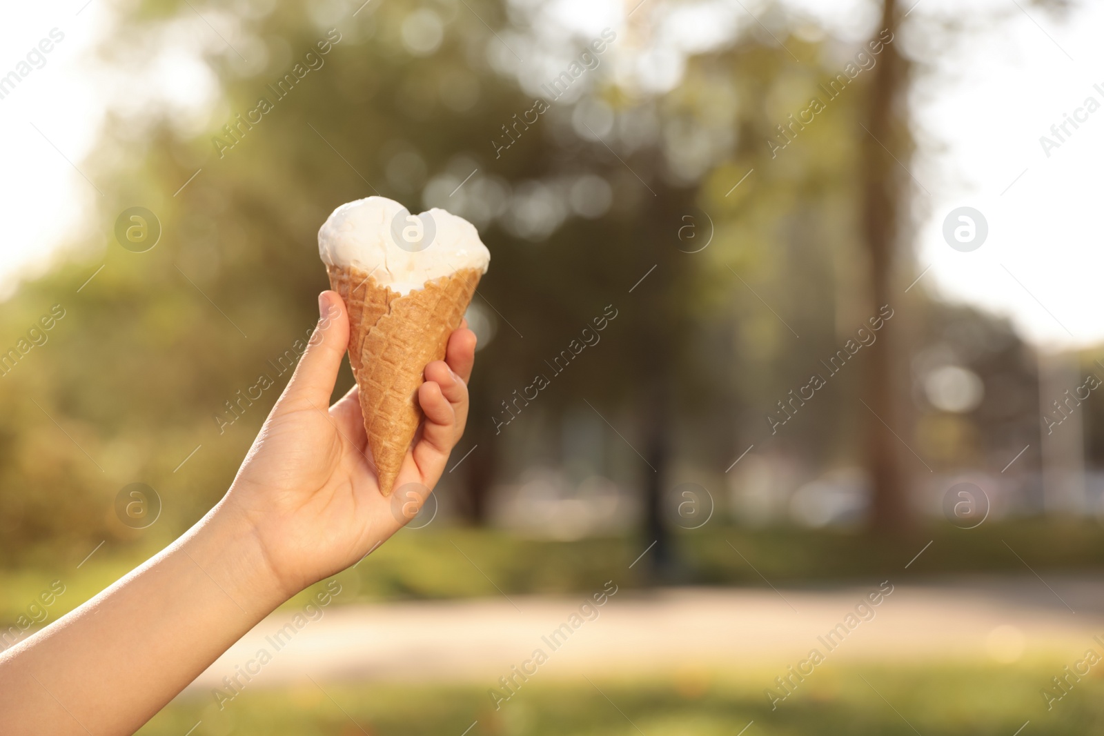 Woman holding delicious ice cream in waffle cone outdoors, closeup of hand. Space for text Photo of Woman holding delicious ice cream in waffle cone outdoors, closeup of hand. Space for text