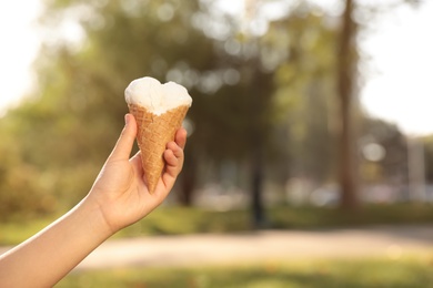 Woman holding delicious ice cream in waffle cone outdoors, closeup of hand. Space for text Photo of Woman holding delicious ice cream in waffle cone outdoors, closeup of hand. Space for text