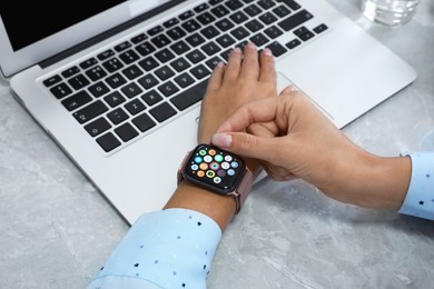 Image of MYKOLAIV, UKRAINE - SEPTEMBER 19, 2019: Woman using Apple Watch at grey table, closeup