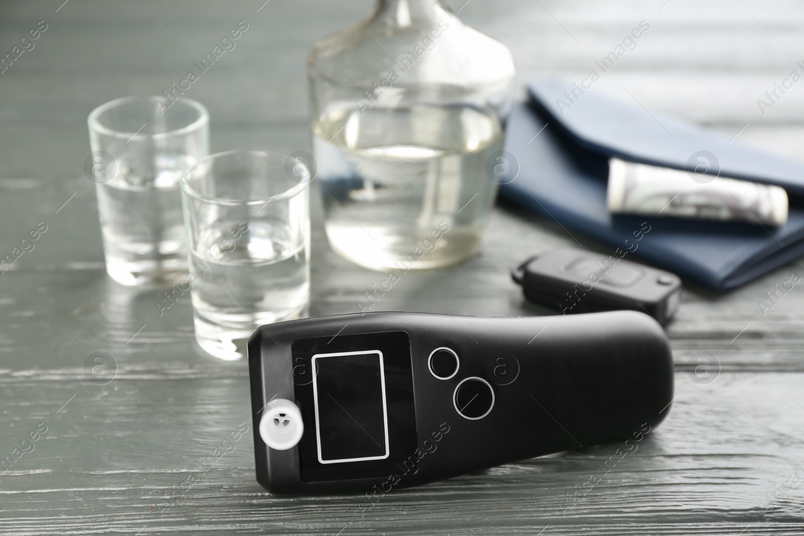 Modern breathalyzer, car key, alcohol and wallet on grey wooden background Photo of Modern breathalyzer, car key, alcohol and wallet on grey wooden background