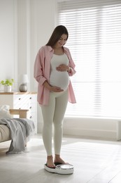 Pregnant woman standing on scales at home Photo of Pregnant woman standing on scales at home