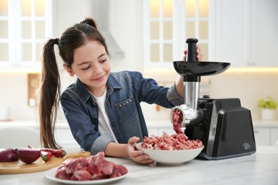 Little girl using modern meat grinder in kitchen Photo of Little girl using modern meat grinder in kitchen