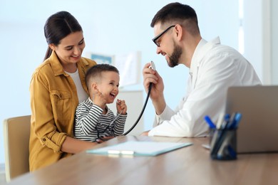 Mother and son visiting pediatrician in hospital. Doctor playing with little boy Photo of Mother and son visiting pediatrician in hospital. Doctor playing with little boy