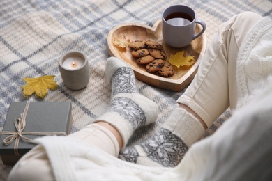 Woman wearing warm socks on checkered plaid, closeup. Cozy season Photo of Woman wearing warm socks on checkered plaid, closeup. Cozy season