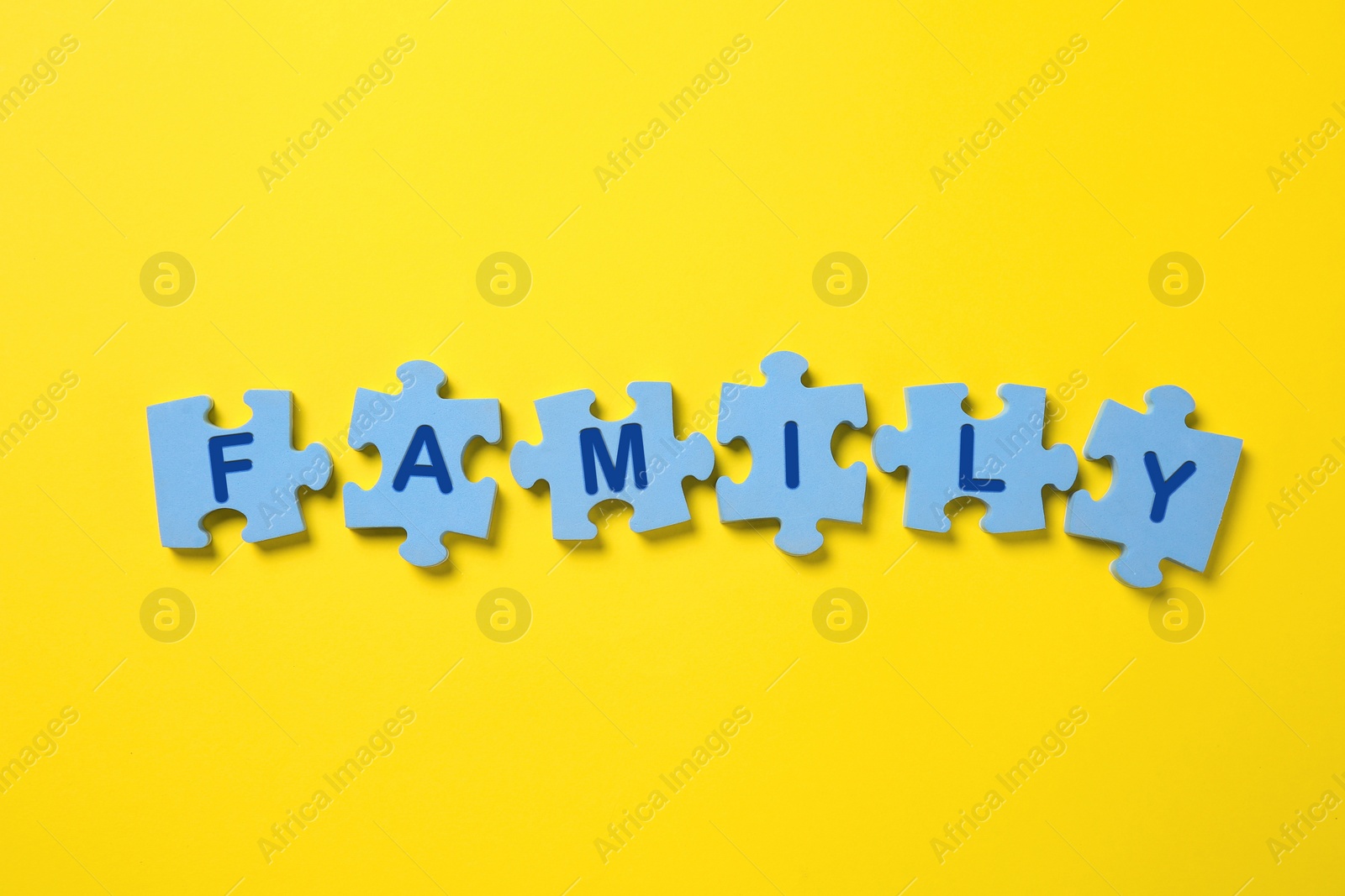 Word Family made of puzzles with letters on yellow background, flat lay Photo of Word Family made of puzzles with letters on yellow background, flat lay