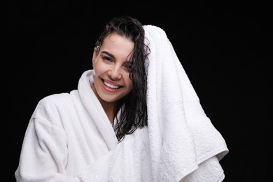Photo of Pretty woman drying hair with towel after washing on black background