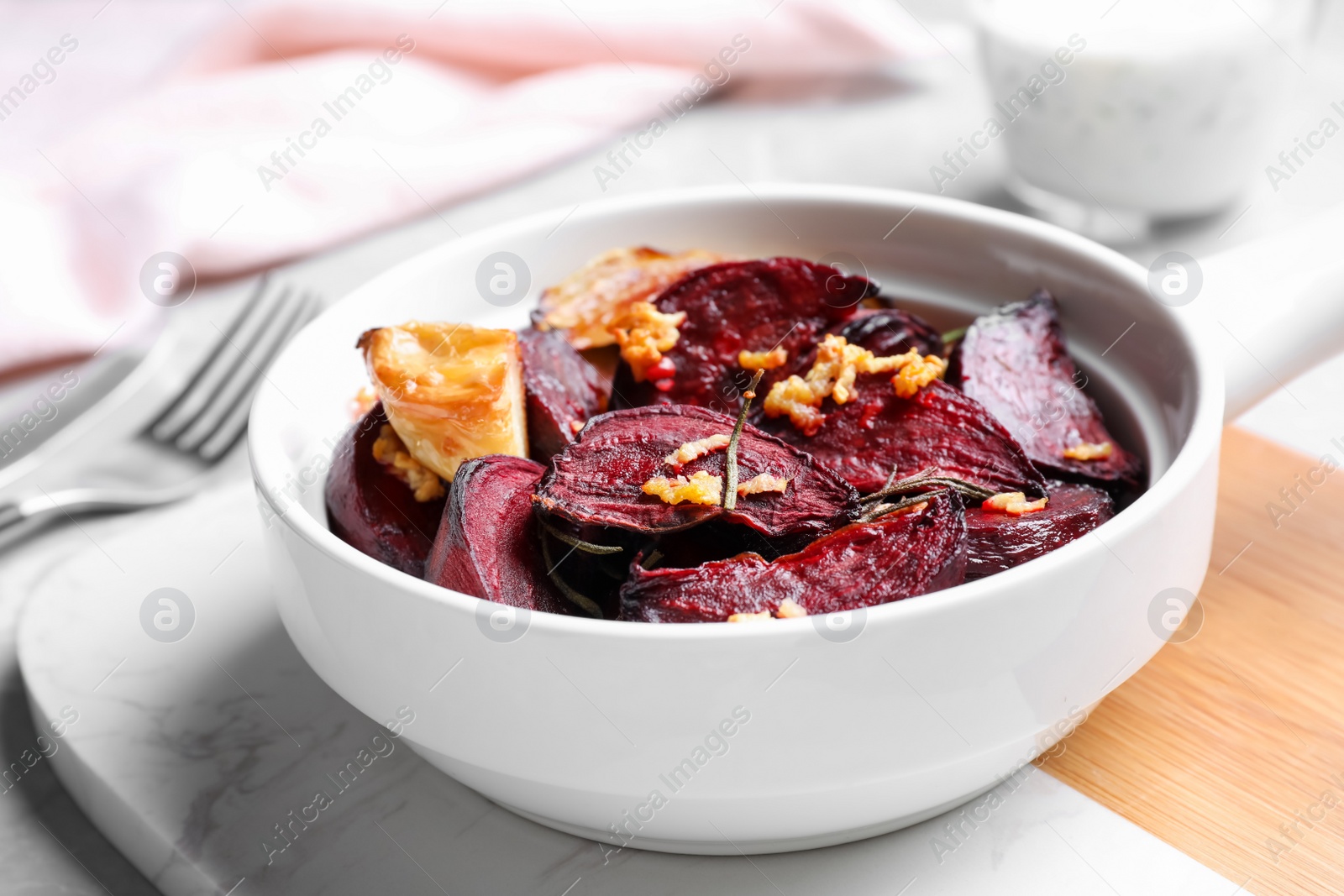 Bowl with roasted beetroot slices, garlic and rosemary on board, closeup Photo of Bowl with roasted beetroot slices, garlic and rosemary on board, closeup