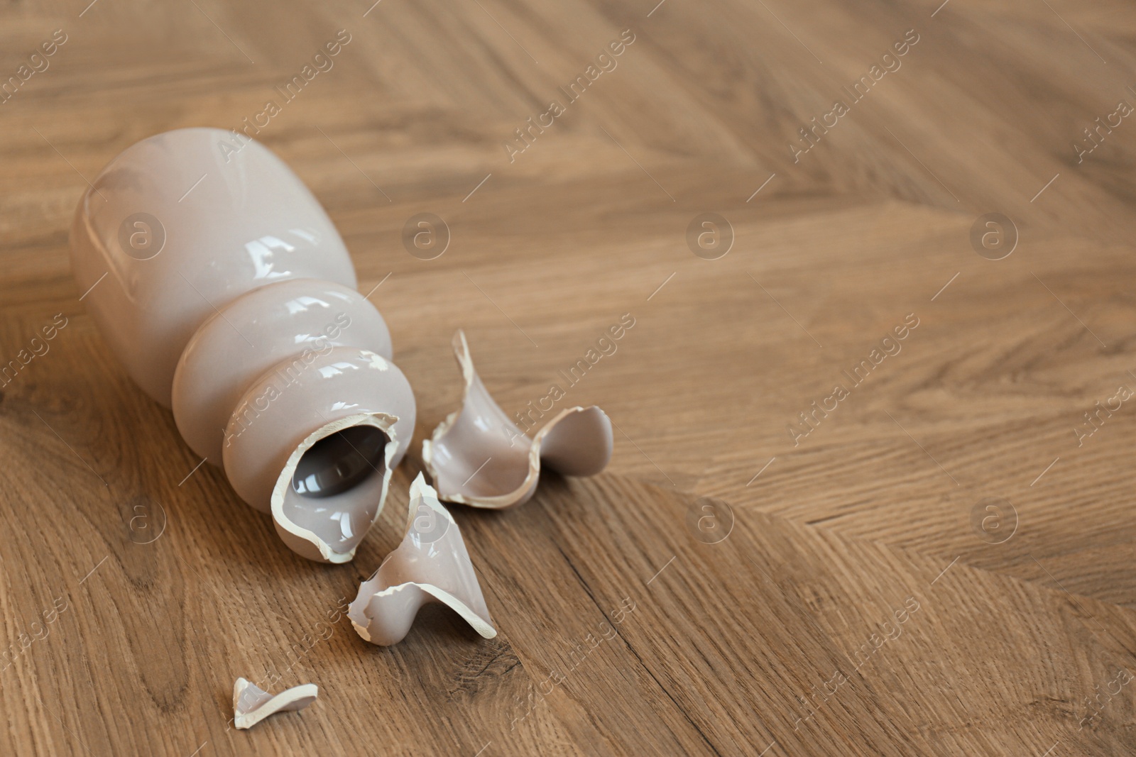 Broken pink ceramic vase on wooden floor. Space for text Photo of Broken pink ceramic vase on wooden floor. Space for text