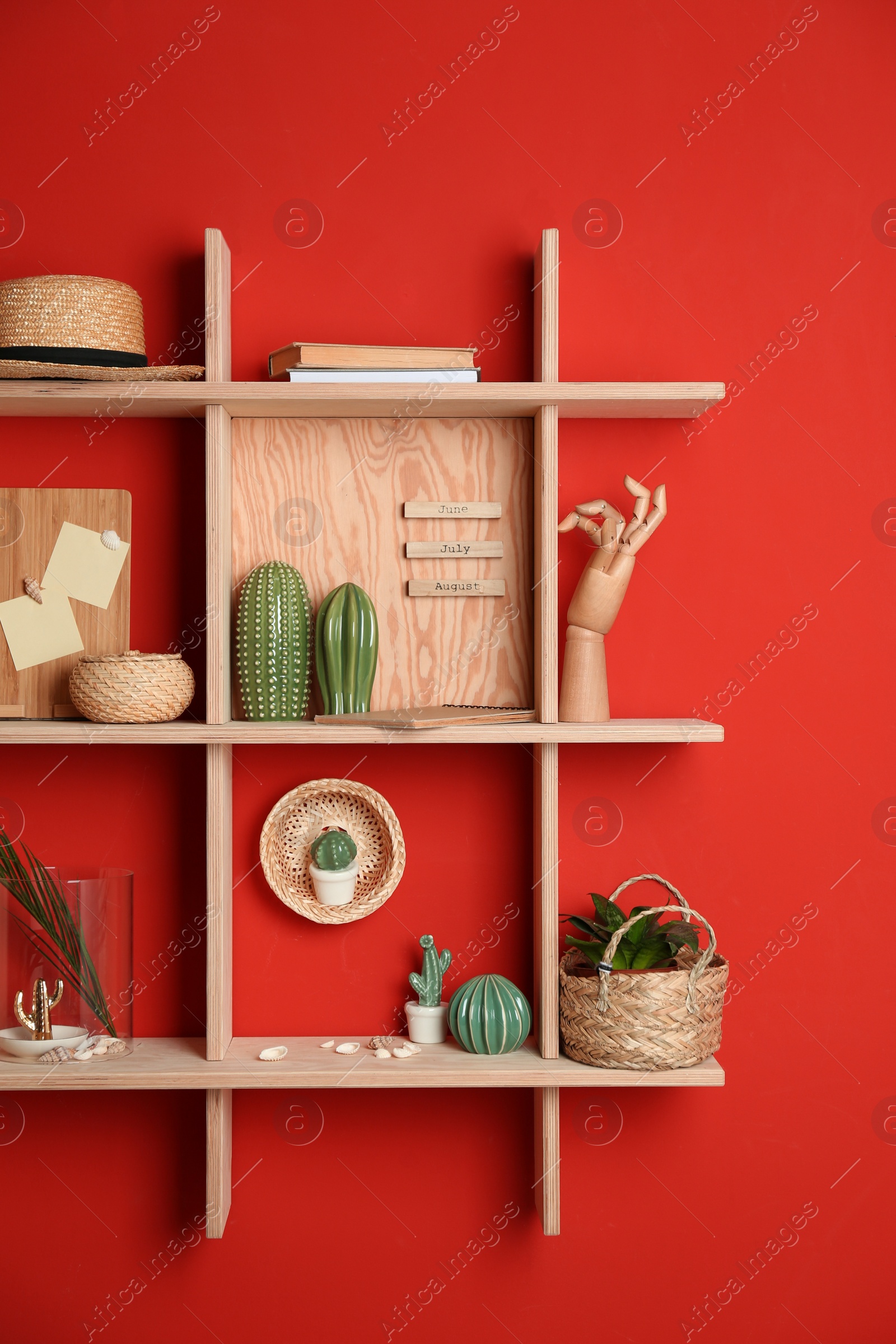 Stylish wooden shelves with decorative elements on red wall Photo of Stylish wooden shelves with decorative elements on red wall