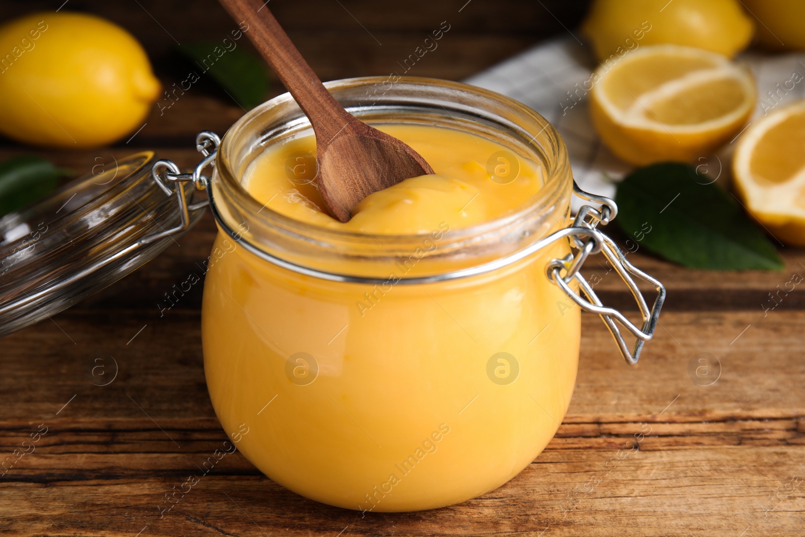 Delicious lemon curd in glass jar on wooden table Photo of Delicious lemon curd in glass jar on wooden table