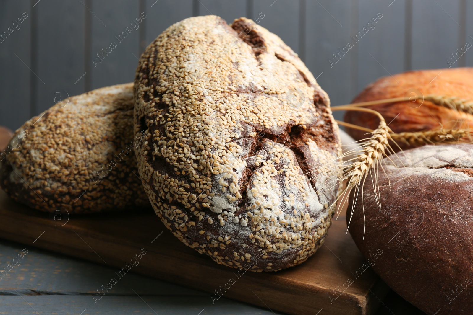 Photo of Loaves of delicious fresh bread on grey wooden table, closeup