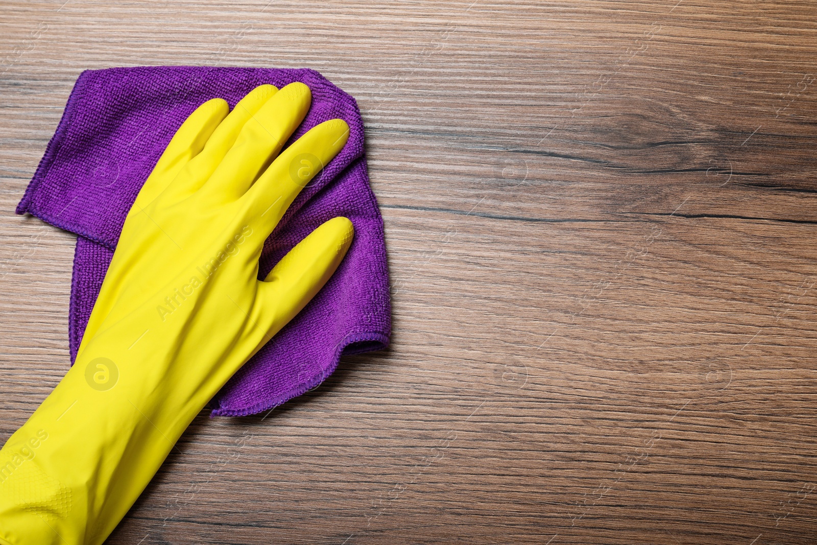 Woman in yellow rubber gloves wiping wooden table with microfiber cloth, top view. Space for text Photo of Woman in yellow rubber gloves wiping wooden table with microfiber cloth, top view. Space for text