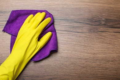 Woman in yellow rubber gloves wiping wooden table with microfiber cloth, top view. Space for text Photo of Woman in yellow rubber gloves wiping wooden table with microfiber cloth, top view. Space for text