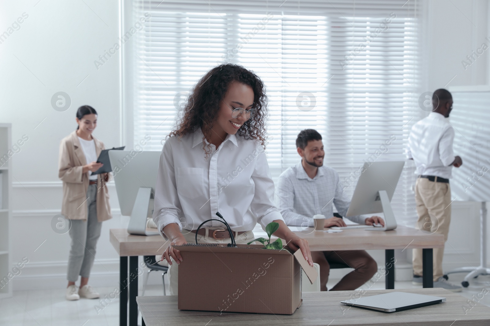 New coworker unpacking box with personal items at workplace in office Photo of New coworker unpacking box with personal items at workplace in office
