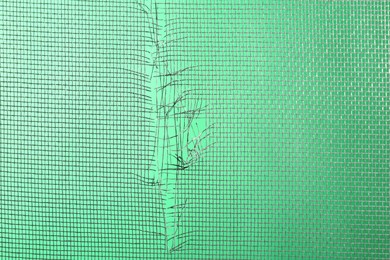 Torn window screen against green background, closeup Photo of Torn window screen against green background, closeup